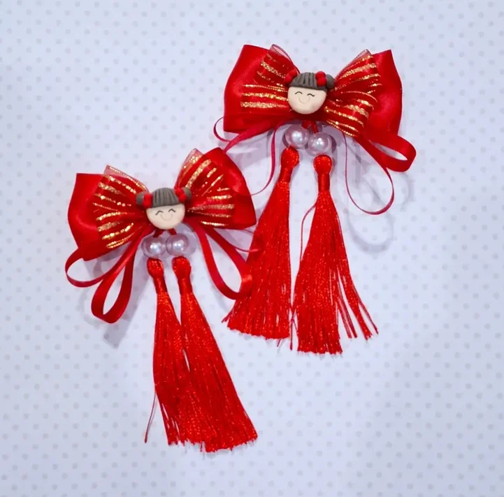 Sepasang pita merah dengan ornamen boneka dan tassel merah
